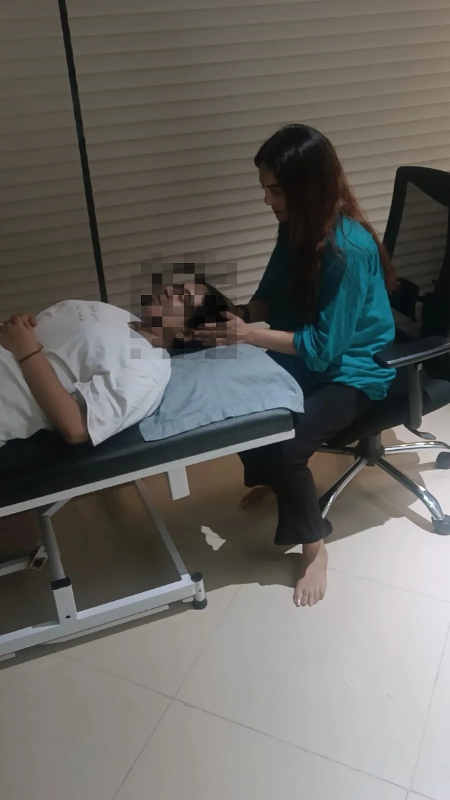 A calm, unhurried one-to-one session with the practitioner seated beside a resting client